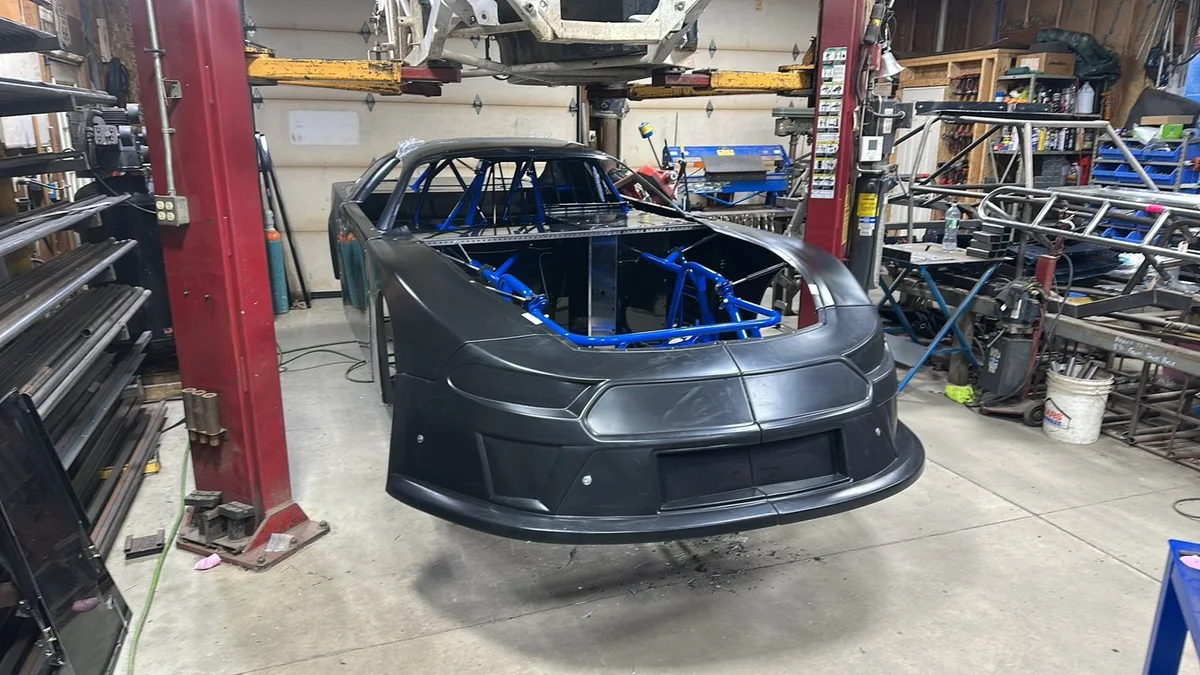 A blue Manimal chassis with its body going on, in the shop